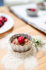 Raw dough with berries for cupcakes decomposed into forms on a baking papper on baking tray decorated ewith flowers. Selective focus. Vintage concept.