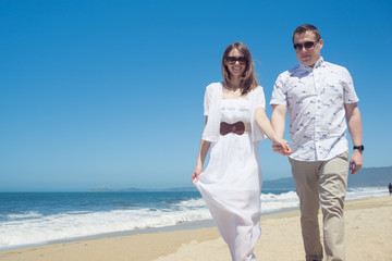 Young romantic couple walking on the beach holding hands
