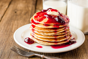 Pancakes with butter and jam on wooden table.