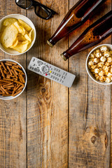film whatching party with beer, crumbs, chips and pop corn wooden background top view mockup