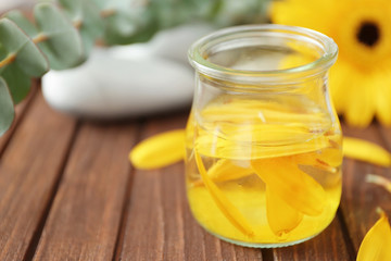 Beautiful spa composition with flower petals in glass jar on table