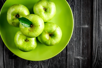 Organic fruits with green apples on plate on dark background top view
