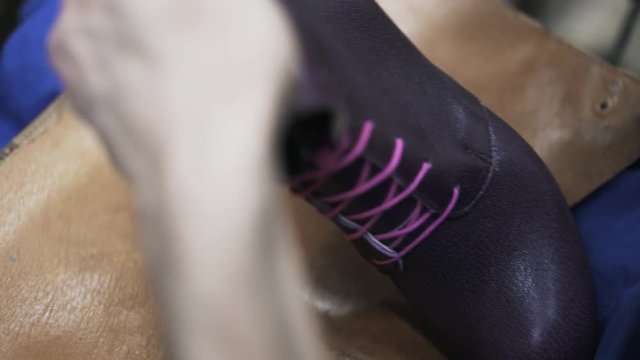 Extreme close up of a cobbler drying a purple woman s boot with purple shoelaces with a dryer. Handheld real time close up shot