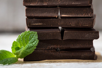 Stack of chocolate slices with mint leaf. dark chocolate over wooden background, selective focus