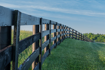 Obraz premium Grassy Hill Cut by Black Fence