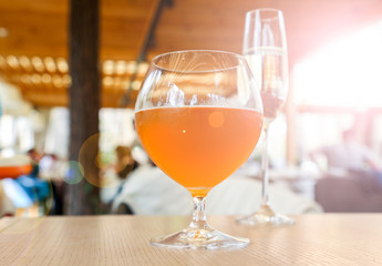 A glass of amber beer and sparkling wine glass on the backround