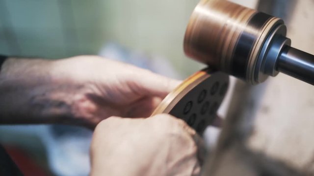 Close up of clobber s hands polishing man s shoe sole at a sander and checking its smoothness with a finger. Handheld real time close up shot