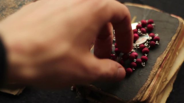 Hand putting down a rosary and a bible.