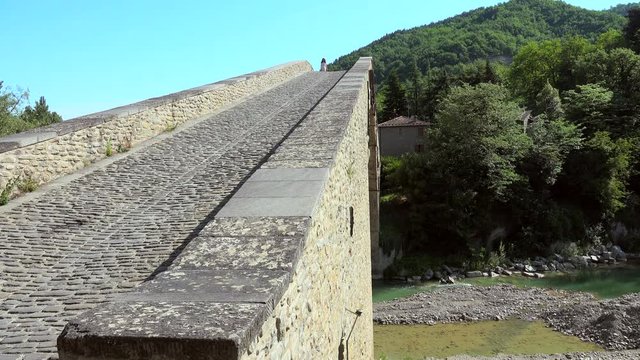 Menopausal tourist In cream colored cocktail dress walking on the steep Renaissance bridge ramp in Europe