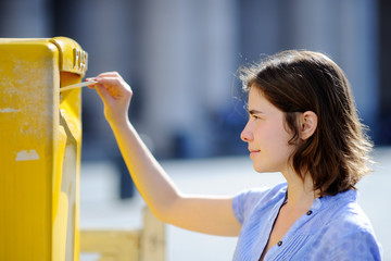 Girl drops a postcard in a mailbox in the Vatican