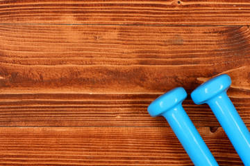 sport equipment concept, blue dumbbells on brown vintage wooden