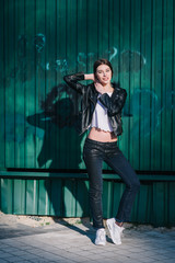 Young beautiful brunette walk in a city against a grundge background and a strong backlight