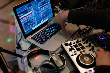 DJ hands on the remote plays or records a track. Using a laptop, headphones and a DJ mixer