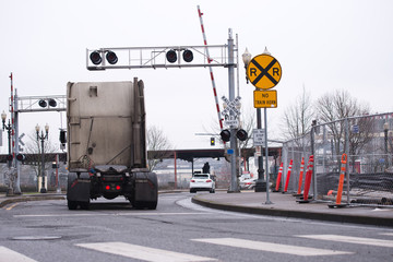 Semi truck tractor moving by railroad crossing