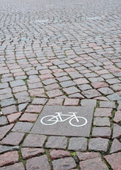 A sign of a bicycle path on a square stone  - obrazy, fototapety, plakaty