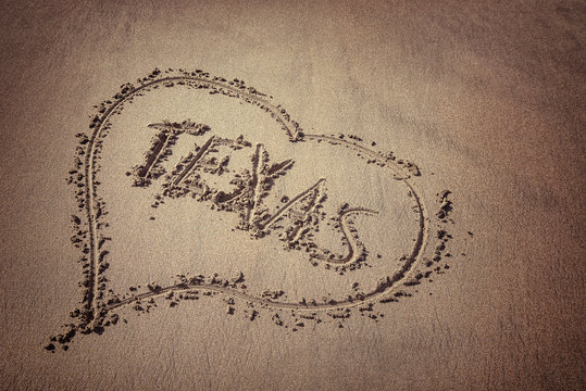 The word Texas and heart drawn on the beach sand. Love Texas concept.