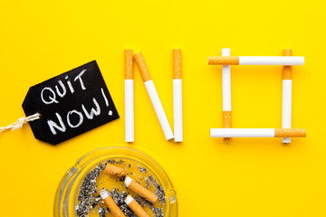 Quit Smoking - No in cigarettes with ashtray with handwritten blackboard  on yellow background
