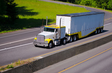 Classic working heavy semi truck with bulk trailer on highway near exit