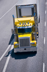 Naklejka premium Big rig yellow classic power semi truck reefer trailer interstate highway