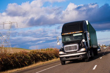 Black Pro powerful modern stylish semi truck and trailer on highway