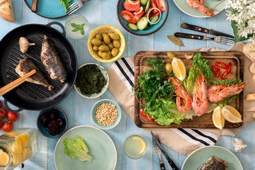 Family dinner table with shrimp, fish grilled, salad, snacks, lemonade