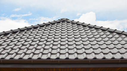 Dark brown ceramic tile roof against blue sky.