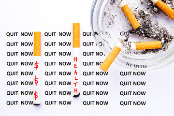 Stop Smoking - Quit Now - with cigarettes and ashtray on printed background
