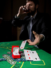 Poker player showing a losing combination in a poker cards, man drinks whiskey from grief