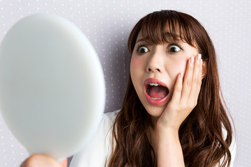 鏡を見て驚く女性