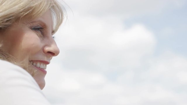 Attractive mature woman smiling outdoors, in slow motion 