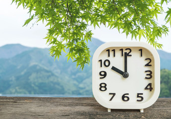 Closeup white clock for decorate in 10 o'clock on blurred mountain view background