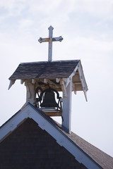 Little old bell tower with cross on roof of provincial wooden church