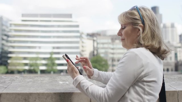 Mature businesswoman on her phone outdoors in the city