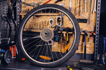 Mountain bike wheel over service tool stand in a workshop.