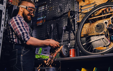 Obraz na płótnie Canvas Mechanic cutting and polish bicycle part in a workshop.