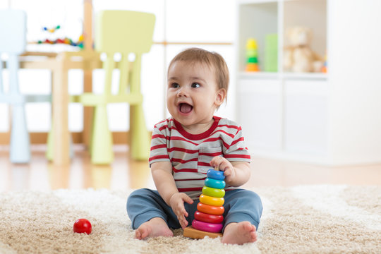 Baby child playing with educational pyramid toys at home. Little kid have fun indoors