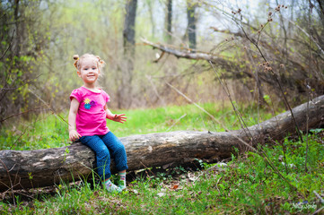 Beautiful little girl on a walk in the park in spring, summer. The girl walks through the woods, resting, having fun. A child in a pink blouse and jeans. Girl with funny tails. The girl knows the worl