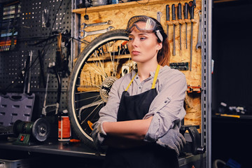 Fototapeta na wymiar Portrait of female bicycle mechanic over tool stand background.