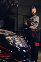 Fototapeta na wymiar Bearded mechanics with crossed arms posing near a car.