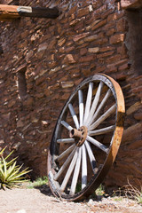 Fototapeta na wymiar Old wheel near a stone wall