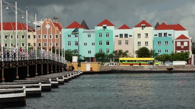The Queen Emma Bridge and pretty colourful buildings in Willemstad Curacao. Taken early morning with people walking across the bridge