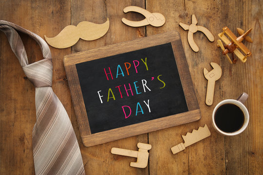top view image of fathers day composition with wooden shape tools, necktie , cup of coffee and blackboard