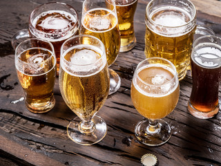 Different glasses of beer on the wooden table.
