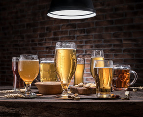 Glasses of beer and snacks on the wooden table.