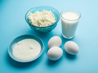 Protein products: cheese cream, milk, eggs on the blue background.
