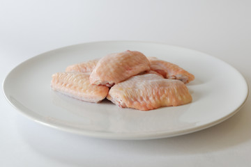 Fresh raw chicken wings on white dish with white background