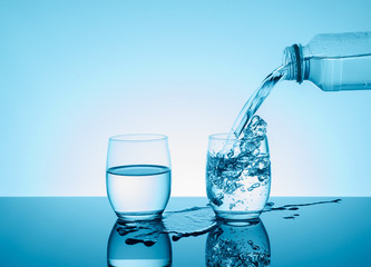 Bottle with creative splashing water in the glass