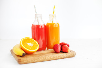 Fruit juice in bottles. Banana, orange and strawberries.  White background. The concept of beverages, health food and vegetarian.