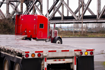 Red classic big rig truck old bridge flat beds turning on road