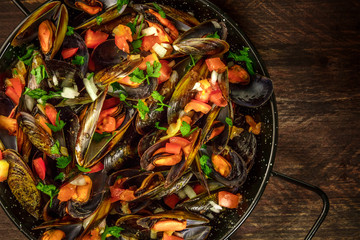 Skillet of marinara mussels on rustic background with copyspace